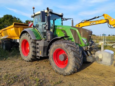 a tractor that is parked in the dirt by a dumpster