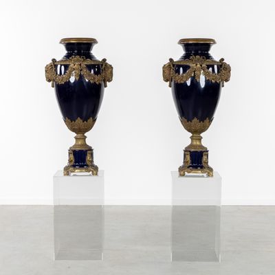 pair of blue and gold vases on pedestals against a white wall