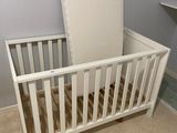 a white crib with a mattress on top of it