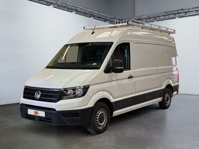 La camionnette blanche est garée dans une grande pièce, avec une échelle sur le toit.