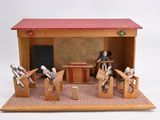 a small wooden model of a classroom with a desk and chairs