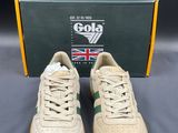 a pair of beige sneakers with green and white laces