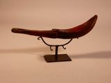 a small wooden boat on a stand on a white surface
