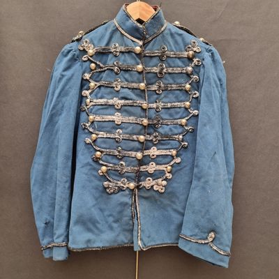 une vieille veste militaire bleue à boutons argentés, suspendue à un cintre