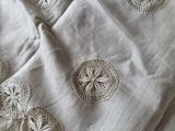 a white table cloth with crochets and tassels on it