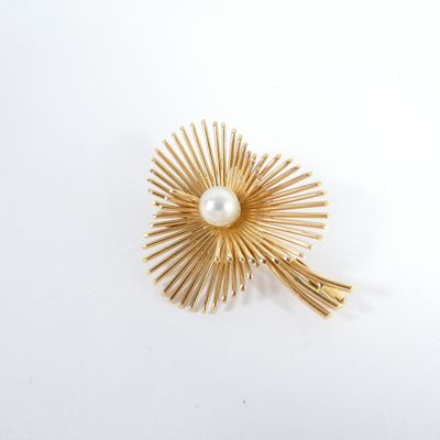 an image of a gold brooch with a pearl in the center