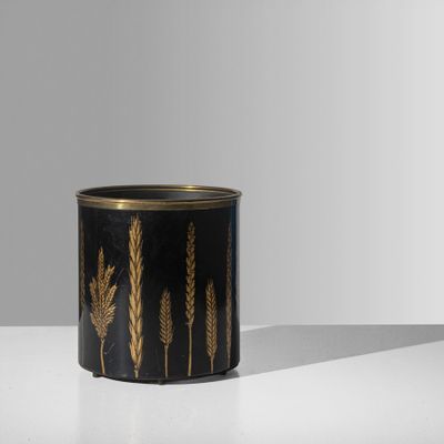 une jardinière noire et dorée posée sur une table blanche