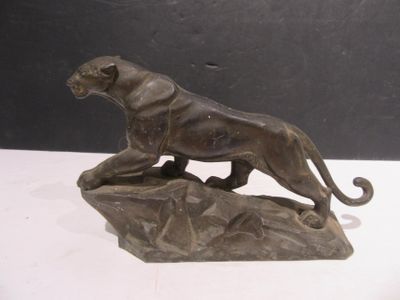 bronze statue of a lion on a rock on a white surface