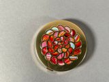 a close up of a gold plate with a colorful flower on it