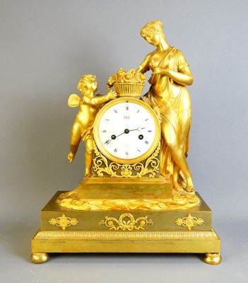 une horloge en or représentant une femme tenant un panier de fleurs