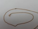 a close up of a gold chain with a clasp on a white surface