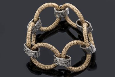 a close up of a silver and gold bracelet on a black surface
