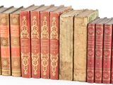 several old books are lined up in a row on a white surface