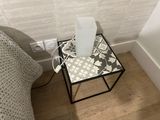 a small table with a lamp on it next to a bed