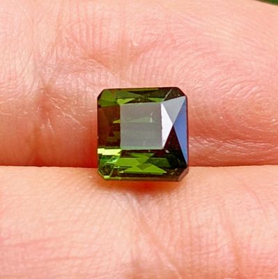 green tourmaline gems are being held in a person ' s hand