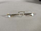 pair of glasses on a table with a laptop in the background