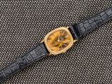 un gros plan d'une montre posée sur une surface noire, avec un cadran jaune