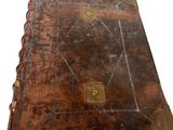 un vieux livre à la couverture brune posé sur une surface blanche
