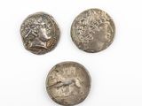trois pièces romaines, dont l'une porte une tête et l'autre un visage