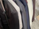 a lot of suits hanging on a rack in a room