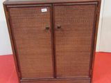 a brown cabinet sitting on a red floor next to a white wall