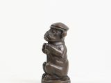 a small bronze monkey figurine with a hat on its head