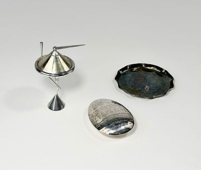 un objet argenté posé sur une surface blanche, à côté d'un autre objet argenté