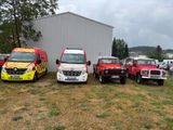 Quatre camions sont garés devant un immeuble aux murs blancs.