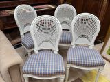 four white cane back chairs with blue and white checkered upholstered upholstered cushions