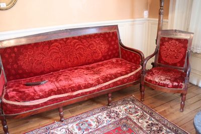 un canapé rouge et deux fauteuils dans un salon