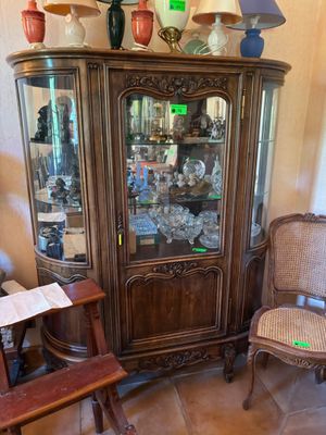 un vaisselier en bois avec une porte vitrée et une chaise