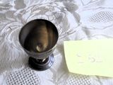 une petite tasse en métal posée sur une table, sur laquelle est posée une note