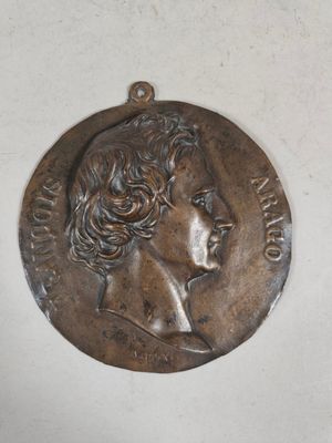 an old bronze medal with a woman ' s face on it