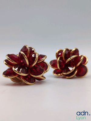 a pair of red and gold flower earrings on a white surface