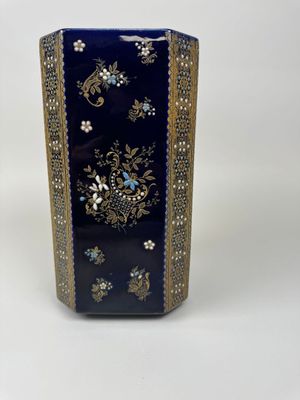 a blue vase with gold trim and flowers on it