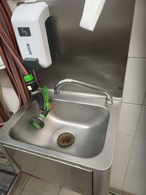 un lavabo dans des toilettes publiques, muni d'un tuyau