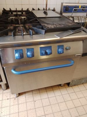 une cuisinière en acier inoxydable avec une poignée bleue dans une cuisine