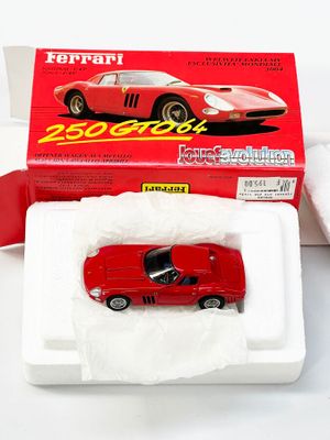 une petite voiture rouge dans une boîte sur une surface blanche