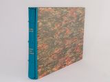 an old book with a blue cover sitting on top of a white surface