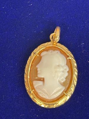 un gros plan d'un pendentif camée doré et blanc sur un fond bleu