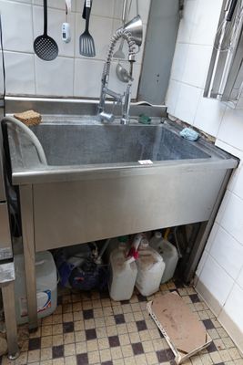 a sink in a kitchen with a lot of clutter on the floor