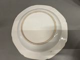 a white plate with a gold rim sitting on a table