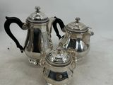 three pieces of silver tea and coffee set on a white surface