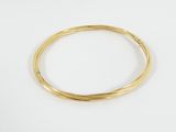 gros plan d'un bracelet en or sur une surface blanche