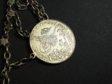 an image of a necklace with a coin on it on a black surface