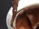 a silver bucket with a brown leather handle on a table