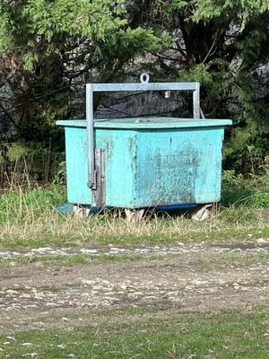 une poubelle bleue posée au milieu d'un champ