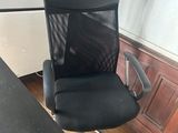 an office chair with a black seat sits in front of a black desk