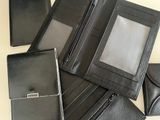 several black leather wallets and a cell phone sitting on a table