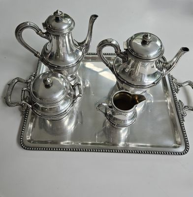 un plateau en argent sur lequel sont posées deux théières en argent et une cafetière